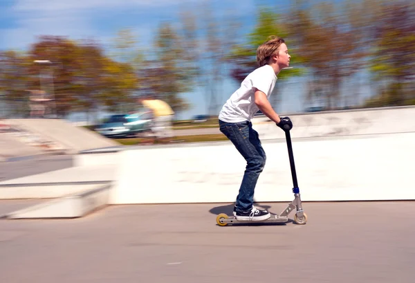 Menino montando com velocidade em sua scooter — Fotografia de Stock