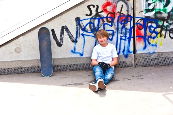 Niño descansando con tabla de skate en el parque de skate — Foto de Stock