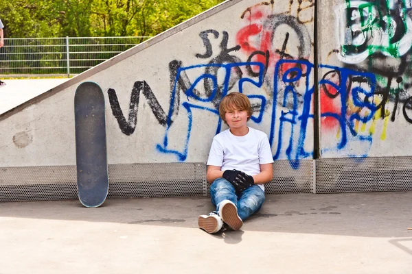 Chłopiec odpoczynku z planszę skate w skate parku — Zdjęcie stockowe