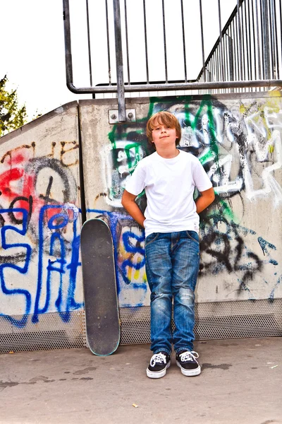 Niño descansando con tabla de skate en el parque de skate —  Fotos de Stock