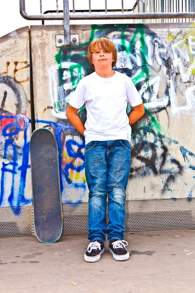 Niño descansando con tabla de skate en el parque de skate —  Fotos de Stock