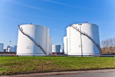 White tanks in tank farm with blue sky clipart