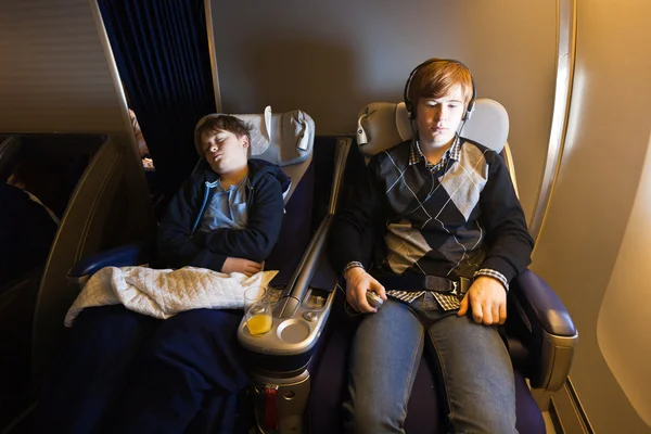 Дети отдыхают и спят в самолете в бизнес-классе — стоковое фото
