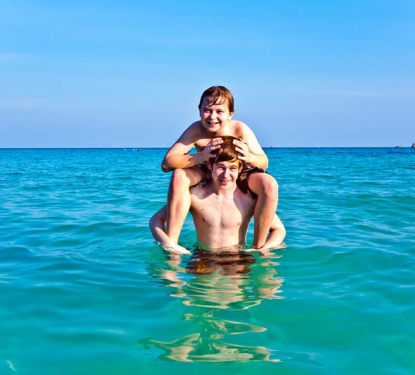 Bröderna njuter det klara varma vattnet på den vackra stranden — Stockfoto