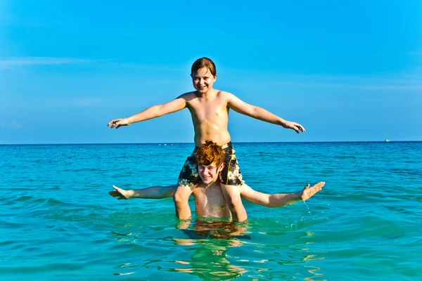 Hermanos están disfrutando del agua caliente clara en la hermosa playa —  Fotos de Stock