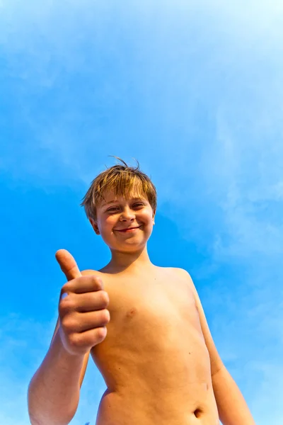 Щасливий хлопчик на пляжі посміхається і показує своє щастя — стокове фото