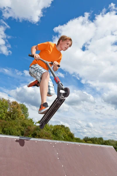 Aranyos fiú megy a levegőben az ő robogó — Stock Fotó