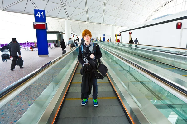 Young teenager on a moving staircase on the way to the gate in t — Stock Photo, Image
