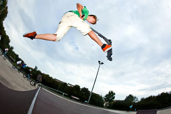 Junge springt mit seinem Roller in die Luft — Stockfoto