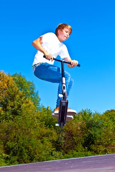 Garçon sautant avec son scooter — Photo