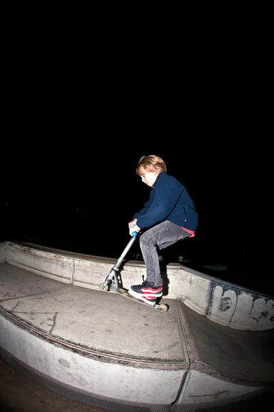 Молодий хлопчик стрибає зі своїм скутером вночі — стокове фото