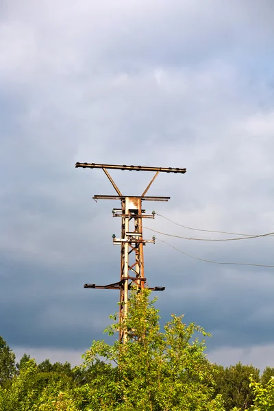 stock image Old rusty electrical tower with dark clouds