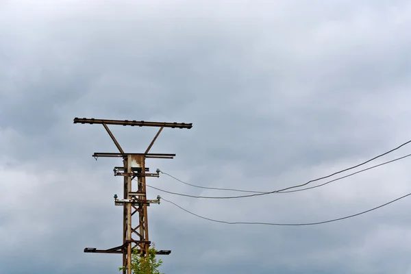 stock image Old rusty electrical tower with dark clouds