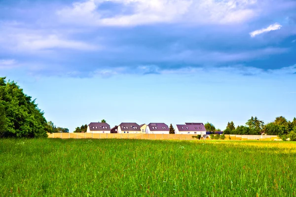 Шумозащитная стена с полем и домами — стоковое фото