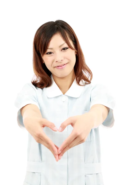 Young asian female nurse shows fingers heart symbol — Stock Photo, Image