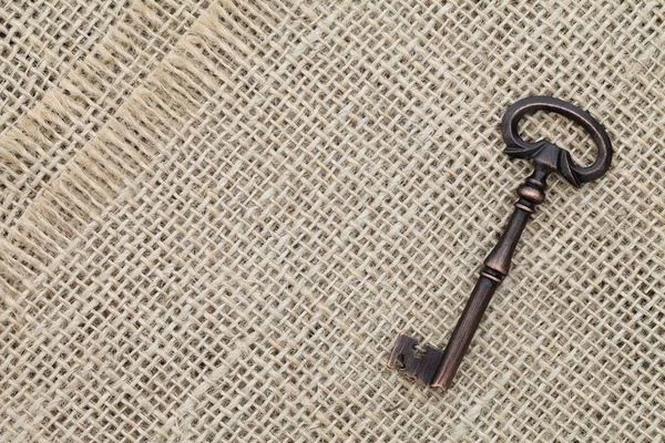 Starý klíč na pytlovina pozadí — Stock fotografie