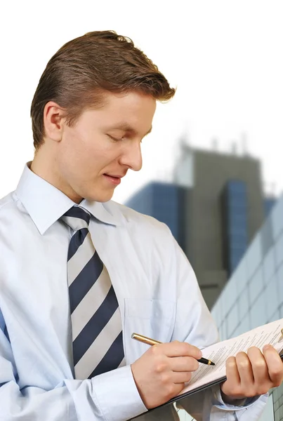 Business man holding a clipboard with corporate buildings — Stock Photo, Image