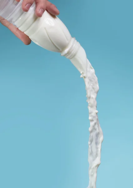 Mjölkflaska i man hand blå bakgrund — Stockfoto