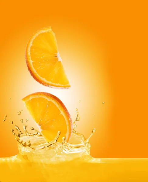 As partes de laranja caem no suco — Fotografia de Stock