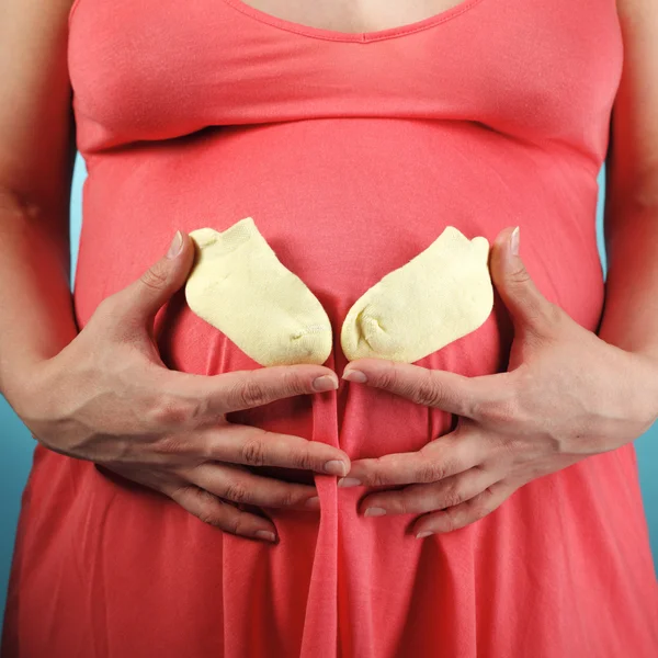 Mulher grávida com botas de bebê — Fotografia de Stock