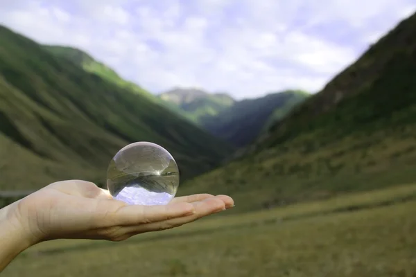 Olhe para o mundo através da bola de cristal na mão — Fotografia de Stock