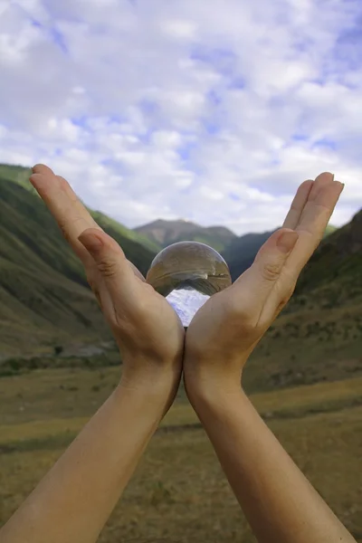 Olhe para o mundo através da bola de cristal na mão — Fotografia de Stock