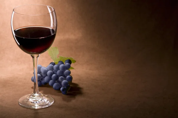 Een glas rode wijn en een tros druiven — Stockfoto