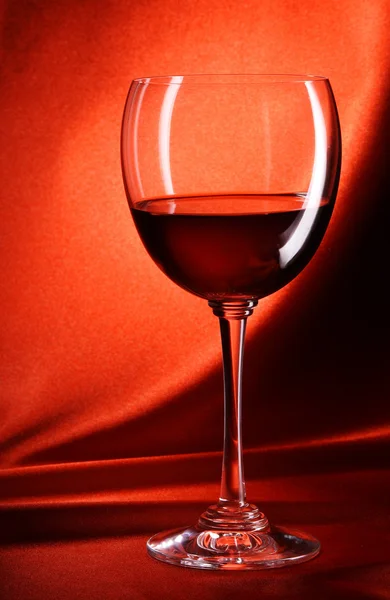 Copo de vinho tinto em um fundo vermelho — Fotografia de Stock