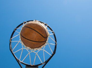 Basketball in net agaisnt blue skies clipart