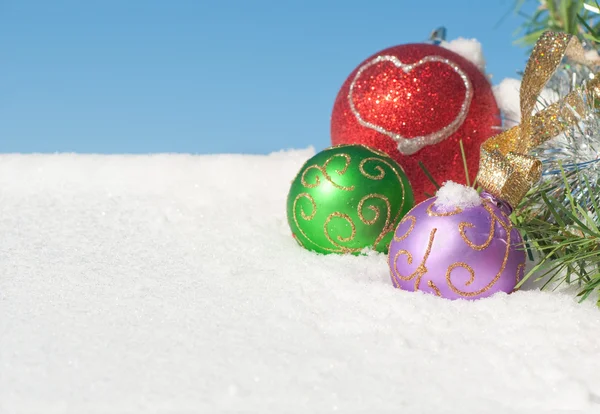 Kolorowe ozdoby świąteczne w śniegu — Zdjęcie stockowe