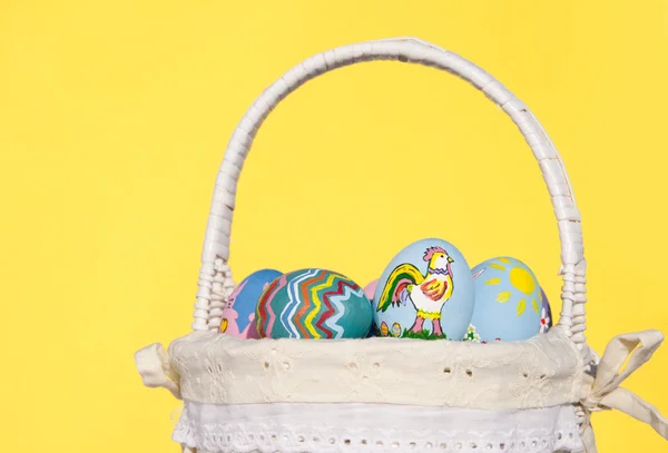 Cesta de mimbre llena de coloridos huevos de Pascua pintados a mano — Foto de Stock