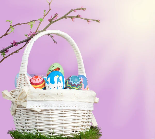 Canasta llena de coloridos huevos de Pascua con ramitas de primavera —  Fotos de Stock