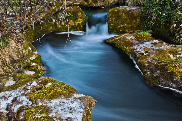 Вода лениво течет между двумя камнями — стоковое фото