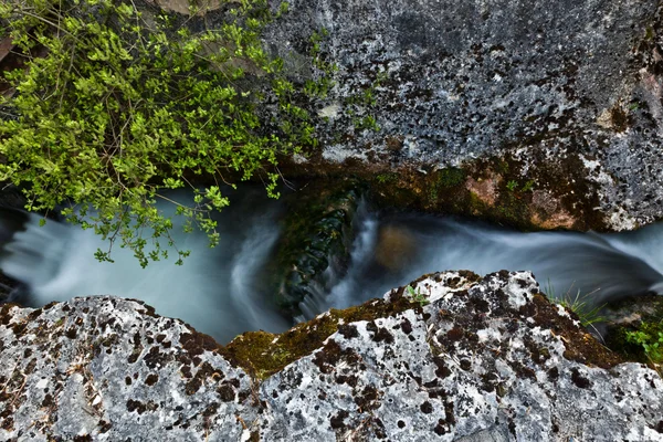 Вода лениво течет между двумя камнями — стоковое фото