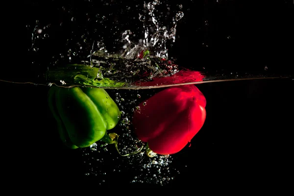 Salpicos de água de pimenta vermelha e verde — Fotografia de Stock