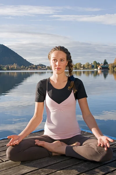 Jeune femme faisant du yoga au bord du lac — Photo