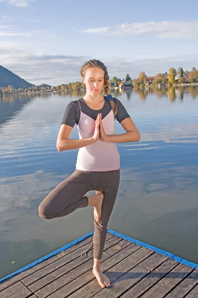 Giovane donna che fa yoga sul lago — Foto Stock