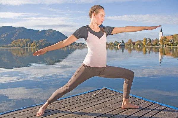 Jovem fazendo ioga junto ao lago — Fotografia de Stock