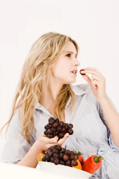 Όμορφη νεαρή γυναίκα τρώει φρούτα σε — Φωτογραφία Αρχείου