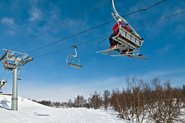 Chair lift with skiers on a blue sky — Stock Photo, Image
