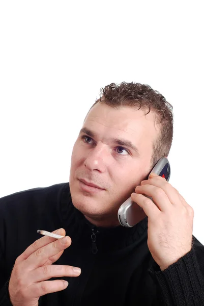 Młody człowiek mówi na jego telefon komórkowy i pali — Zdjęcie stockowe