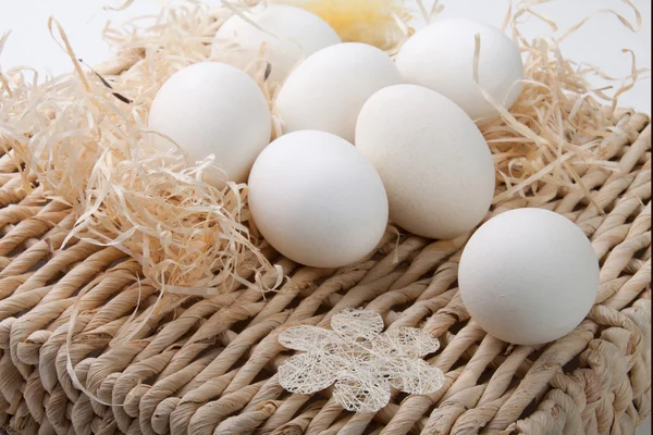 Huevos blancos acostados sobre un soporte de paja — Foto de Stock