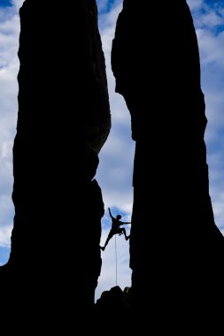 Rock climber reaching across a gap. clipart