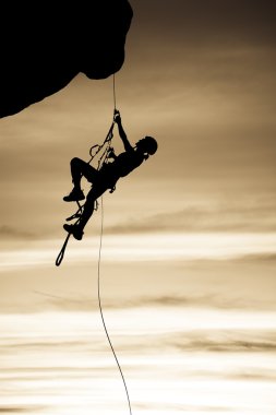 Rock climber dangling from a rope. clipart