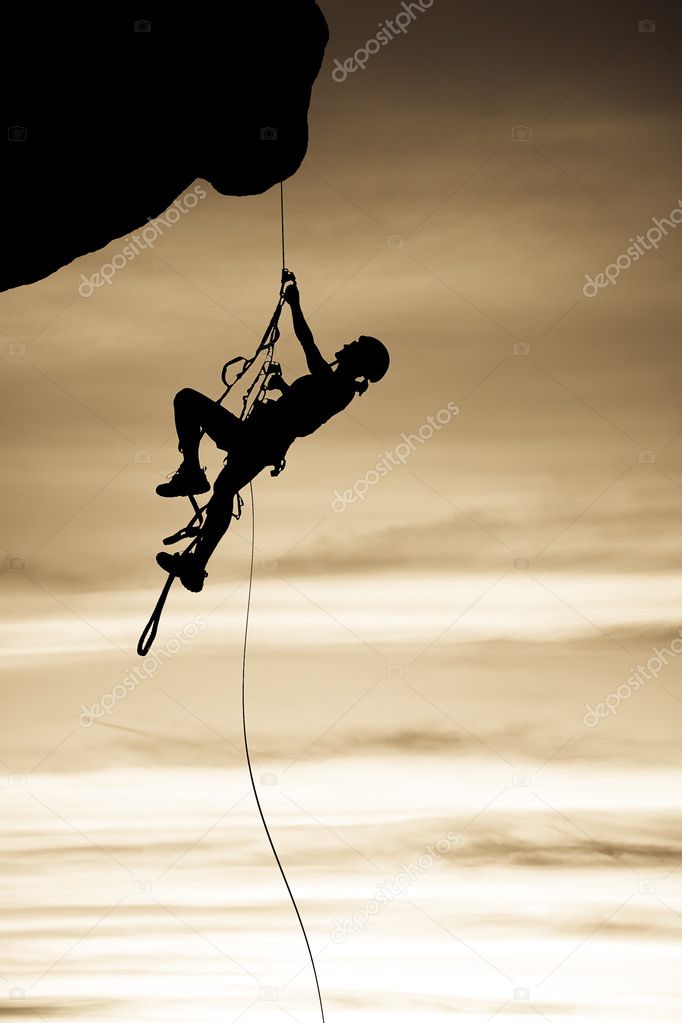 Rock climber dangling from a rope.
