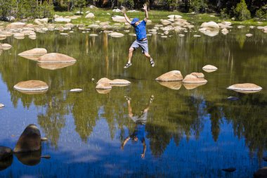 Rock hopping across an alpine lake clipart