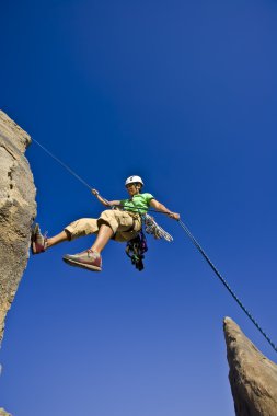 Rock climber rappelling. clipart