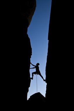 Rock climber clinging to a cliff. clipart