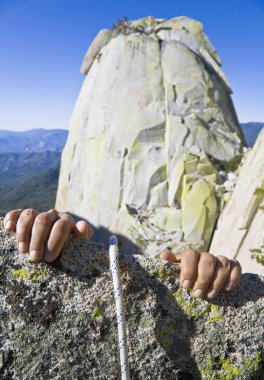 Rock climber clinging to a cliff. clipart