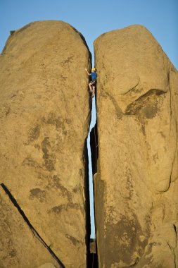 Rock climbing a split pillar. clipart